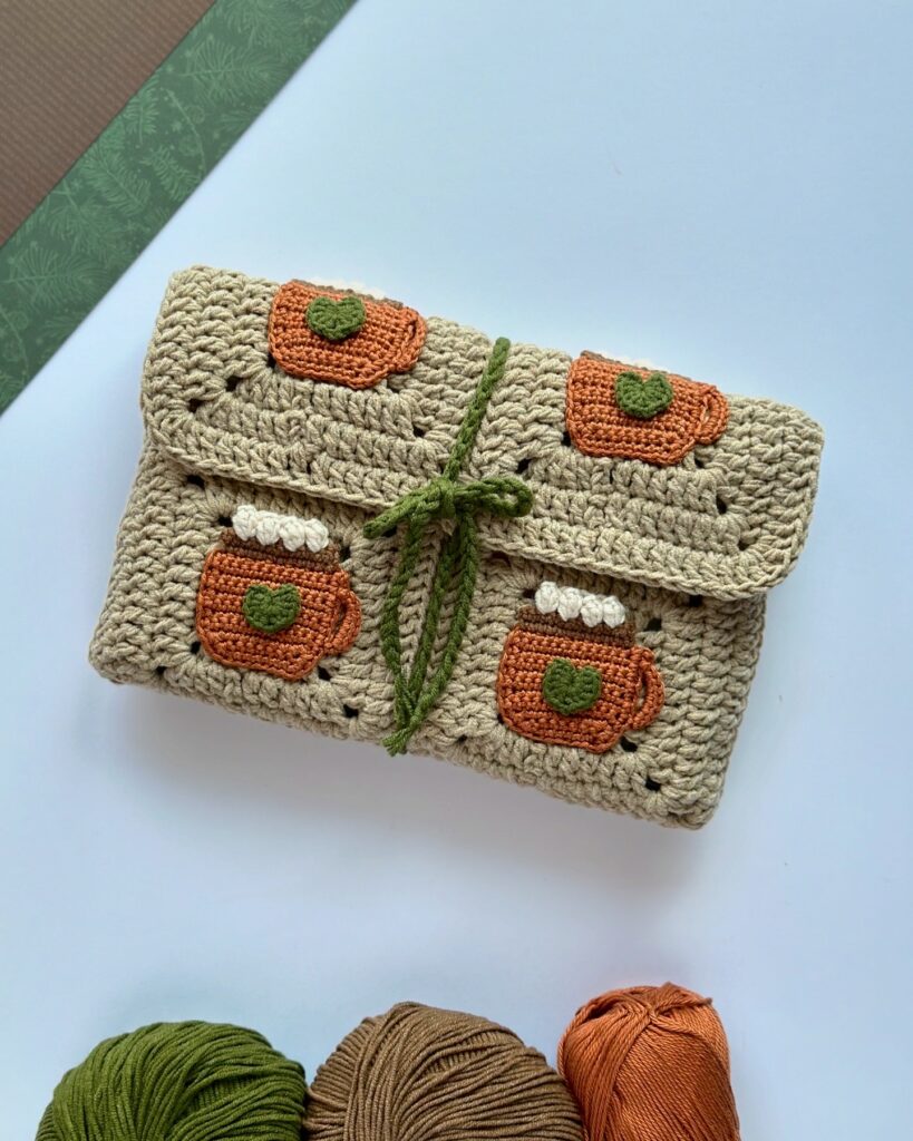 etui na książkę wykonane na szydełku, ozdobione aplikacjami kubeczków z kawą.