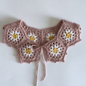 ażurowy kołnierzyk wykonany na szydełku. wiązany na troczki. kolor to pudrowy róż ze stokrotką pośrodku.