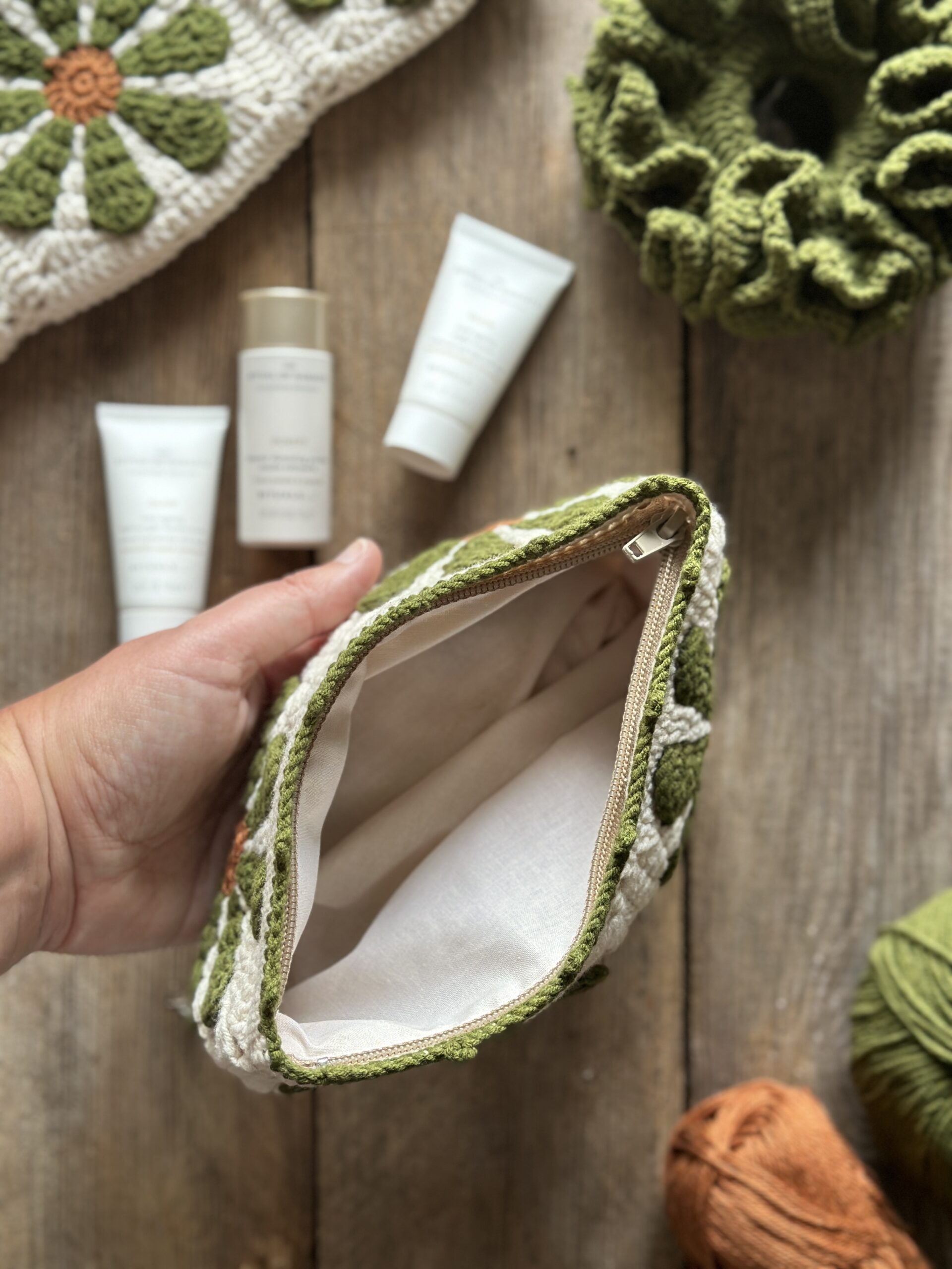 dziergany organizer do torebki z bawełnianą podszewką, zapinany na zamek. styl boho. kolor główny to ecru, kwiaty w kolorach rdzawo oliwkowych.