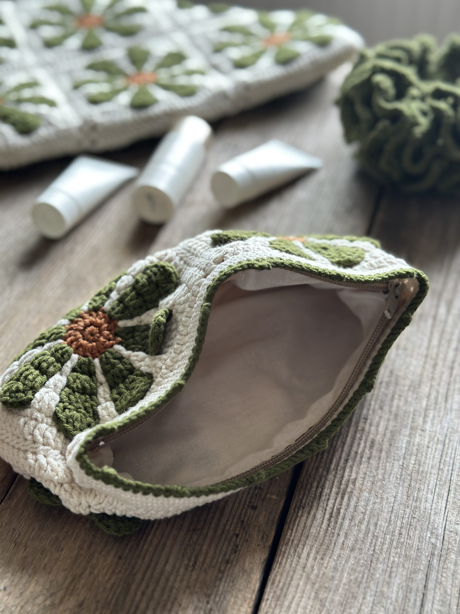 dziergany organizer do torebki z bawełnianą podszewką, zapinany na zamek. styl boho. kolor główny to ecru, kwiaty w kolorach rdzawo oliwkowych.