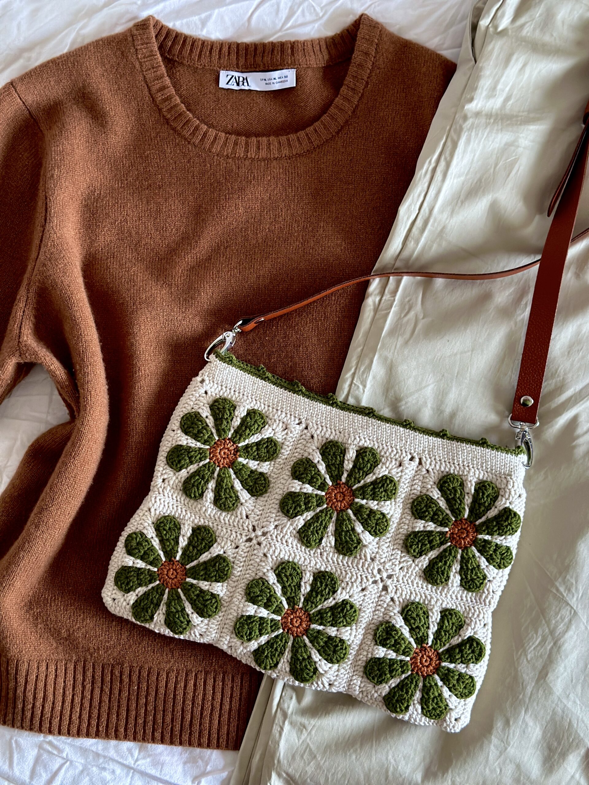 dziergana torebka w retro kwiaty. tło beżowe, kwiaty miedziano oliwkowe. torebka ma pasek ze skóry naturalnej z możliwością regulacji długości. posiada również podszewkę z kieszonką i jest zapinana na zamek błyskawiczny. jest to polskie rękodzieło