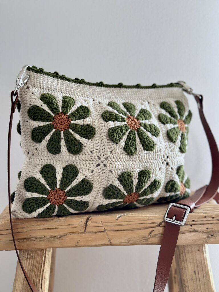 niepowtarzalna torebka wykonana na szydełku. torebka jest w beżowym kolorze w kwiaty w kolorze oliwkowym. ma podszewkę z kieszonką, jest zapinana na zamek. posiada skórzany pasek z możliwością regulacji długości. idealna na co dzień.