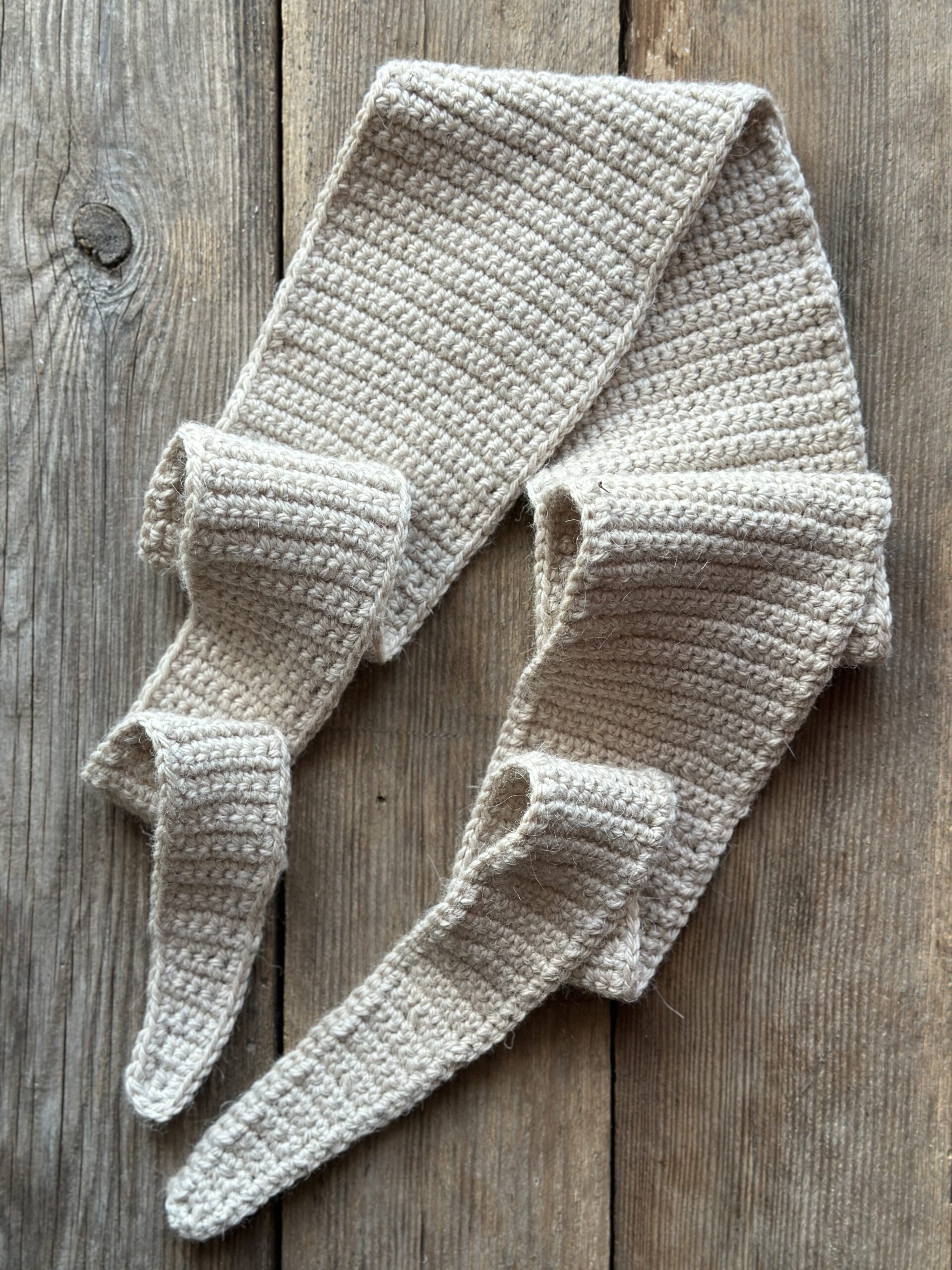 szalik długi ale wąski, dziergany na szydełku. wykonany z przędzy, która jest mieszanką wełny i alpaki. nie gryzie i nie drapie. kolor to jasny, ciepły beż. Szalik można wiązać na kilka sposobów, jego długość to około 1,5 metra.