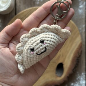 szydełkowy brelok pieróg ręcznie robiony. wykonany z miękkiej włóczki z dołączonym kółkiem i karabińczykiem. ma wyszyty uśmiech i bezpiecznie oczka. unikalny dodatek do plecaka, torebki, kluczy.