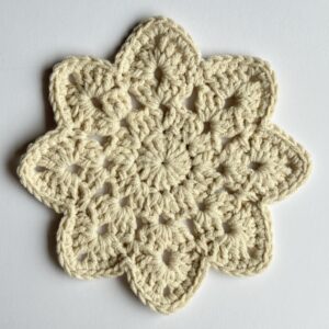 Ręcznie robiona podkładka pod kubek w kwiatowym kształcie, jednolity beżowy kolor.