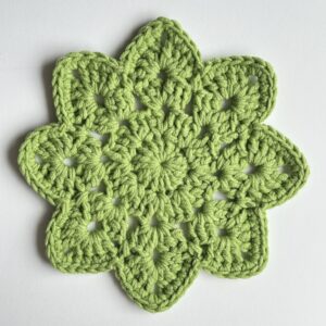 Szydełkowa podkładka na stół w kolorze soczystej zieleni w kształcie kwiatowym.